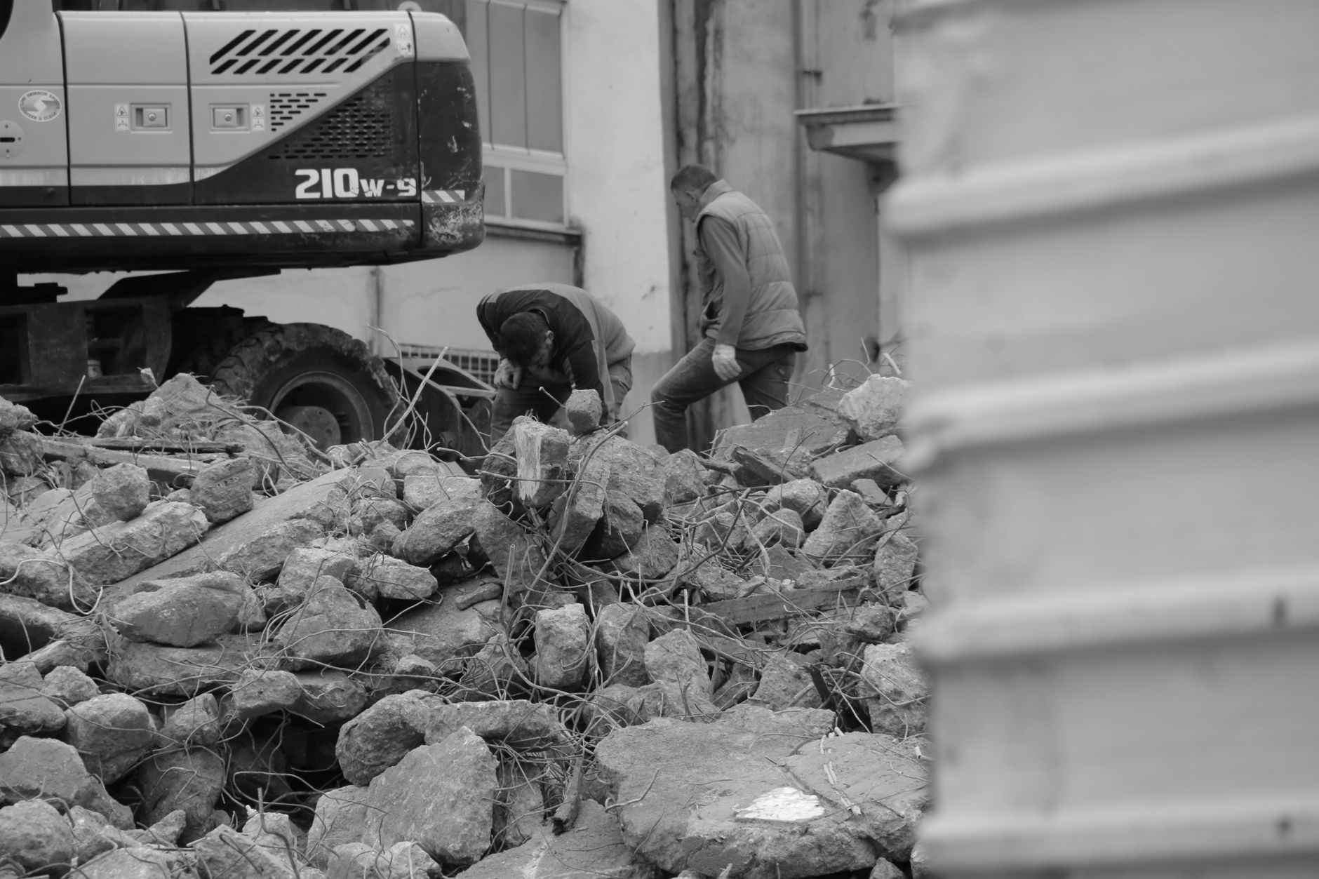 Black and white photo of workers and heavy machinery at a demolished construction site